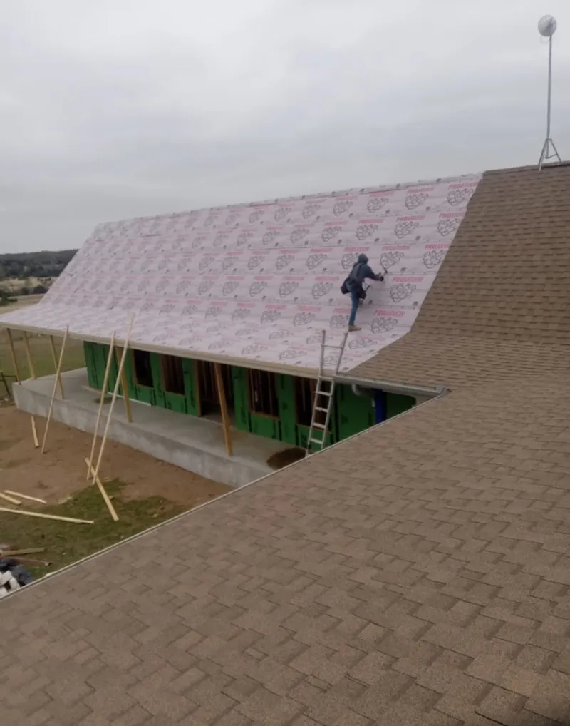 Worker preparing underlayment for a metal roof installation in Battle Ground